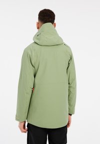 Giacca impermeabile verde con cappuccio, caratterizzata da una texture liscia, funzioni regolabili e un accento arancione sulla cerniera.