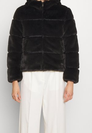 Czarna krótka kurtka puchowa z sztucznego futra z przednim zamkiem błyskawicznym i kapturem, noszona z białymi plisowanymi spodniami z wysokim stanem.