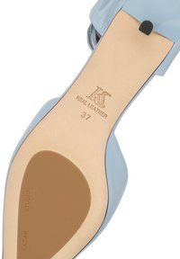 Semelle de chaussure plate en cuir bleu clair montrant la taille 37, la marque Kazar Studio, et « Cuir véritable » embossé sur une semelle intérieure beige.