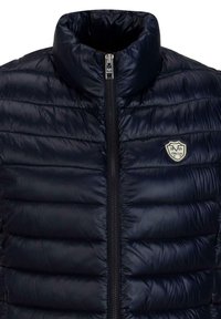 Marinefarbige gepolsterte Jacke mit hohen Kragen und durchgehendem Reißverschluss. Enthält ein Logo-Patch und hat eine glatte, glänzende Textur.