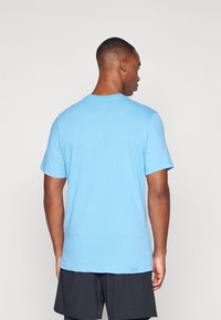 Maglietta azzurra a maniche corte in cotone, con scollo rotondo e vestibilità comoda, dettagli di cucitura visibili all'orlo.