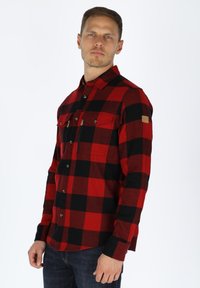 Rood en zwart geruit flanellen shirt met lange mouwen, twee borstzakken met kleppen en een knoopsluiting aan de voorkant. Heeft een gestructureerde stof.