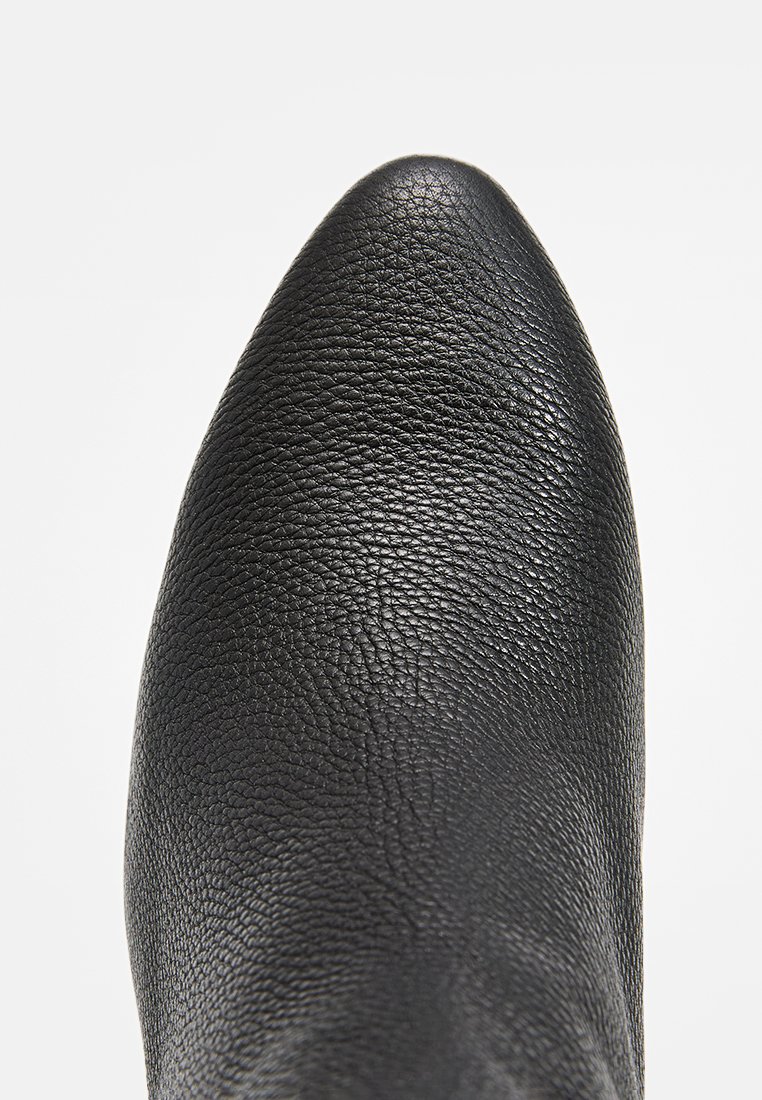 Czarne skórzane botki za kostkę o teksturowanym wykończeniu, z ostrym noskiem i bez widocznych elementów metalowych. Powierzchnia jest gładka z subtelnymi wzorami słojów.