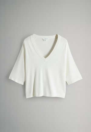 Hvid cropped T-shirt med V-hals, korte ærmer og ribbet hals. Blød tekstur og afslappet pasform. Ingen mønstre eller hardware-detaljer.