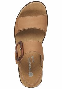 Sandal in pelle tan con due ampie cinghie, una fibbia in stile legno e una soletta imbottita. La suola presenta un contorno scuro a contrasto.
