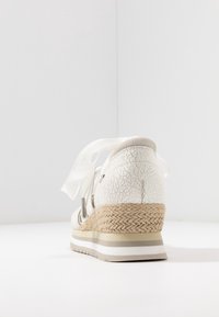 Vita espadrille sneakers med sprickig textur på ovandelen, vävd sisalsula och vita satinfjädrar. Den har en platå och gummisula.