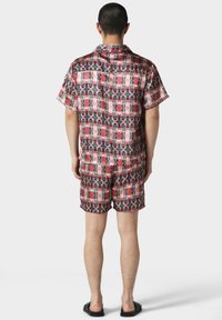 Set di camicia a maniche corte e pantaloni corti in un motivo rosso e nero con grafiche intricate. Realizzato in un tessuto morbido con una vestibilità comoda.