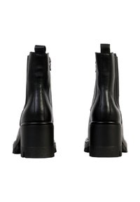 Bottes à cheville en cuir noir avec un talon épais, une fermeture à glissière et une texture lisse. Comportent des détails de couture verticale sur les côtés.