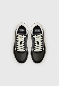 Baskets noires et grises en mesh et cuir, avec des lacets blancs, un bout arrondi et un logo sur la languette.