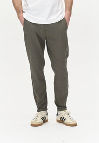 Pantalons fuselés à motif vichy gris en tissu texturé, dotés de poches latérales et d'un ajustement confortable, associés à des baskets beiges.