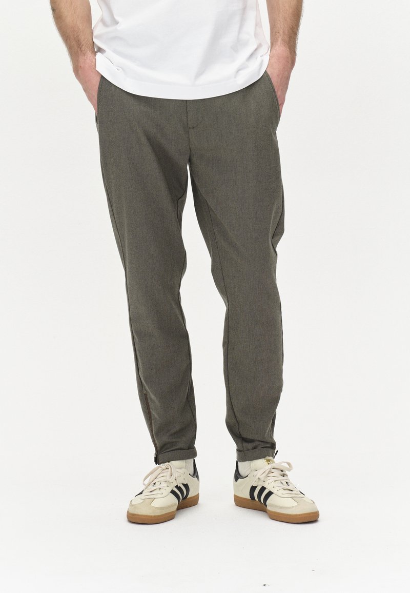Pantalons fuselés à motif vichy gris en tissu texturé, dotés de poches latérales et d'un ajustement confortable, associés à des baskets beiges.