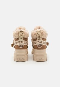 Chunky mid-top sneakers in tan suede with cream-colored faux fur collar. Features a beige rubber sole and branded straps on the back.