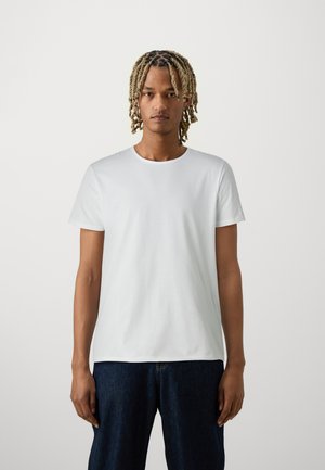 T-shirt en coton blanc à manches courtes et encolure ronde, avec une texture lisse et une coupe décontractée, associée à un jean en denim noir.