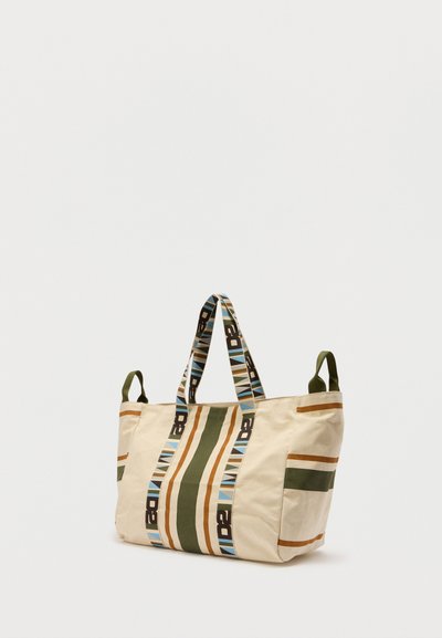 Sac fourre-tout en toile avec des rayures verticales vertes, marron et bleues, des anses à motifs, des poches latérales et une base rectangulaire.