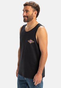 Camiseta sin mangas de algodón negro con escote redondo y sisas, que presenta un diseño bordado en forma de diamante multicolor en el pecho.