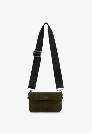 Bolso bandolera de ante verde oliva con una correa negra que lleva el nombre de la marca, herrajes plateados y un diseño con solapa plegable.