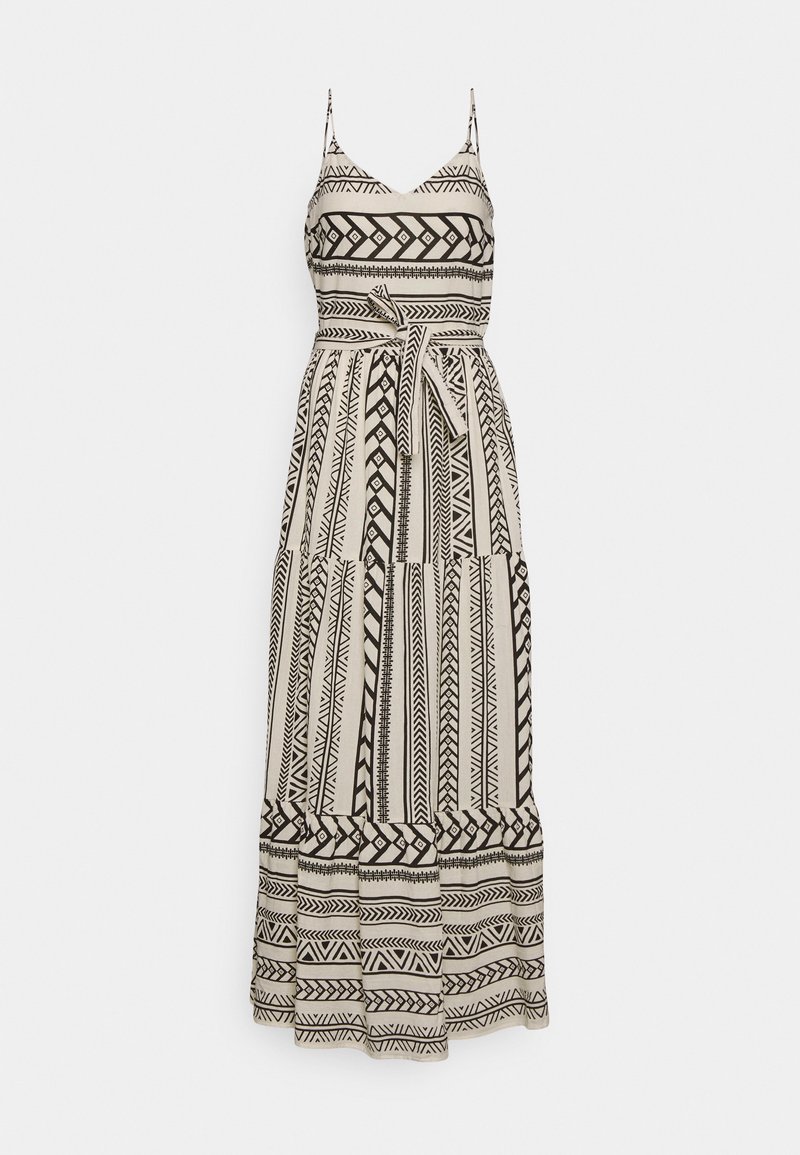 Robe longue sans manches avec fines bretelles, motifs géométriques et tribaux noirs sur tissu blanc, et ceinture nouée à la taille.