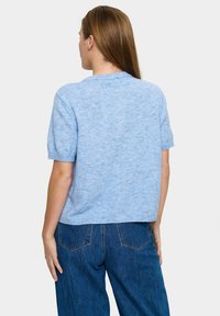 Jasnoniebieski sweter z krótkim rękawem o miękkiej, dzianinowej teksturze. Dekolt jest okrągły, z krojem do wysokości talii i ściągaczami.