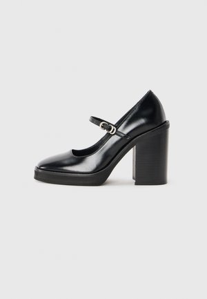 Black patent leather high heel shoe with a round toe, ankle strap, silver buckle detail, and a chunky block heel.