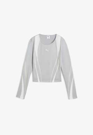 Šedý crop top s dlhým rukávom a bielymi vlnitými akcentmi, vyrobený z hladkej tkaniny. Má okrúhly výstrih a malé logo na prednej strane.