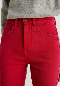 Røde denim jeans med høj talje, forlommer og lukning med metalknap. Har en glat tekstur og et klassisk fem-lomme design.