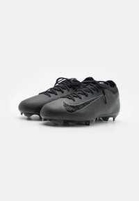 Black soccer cleats with textured synthetic upper, featuring a reflective swoosh logo and turquoise-studded outsole for traction.