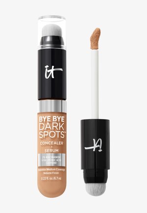 Tube de correcteur et de sérum étiqueté "Bye Bye Dark Spots" avec applicateur et pinceau intégré, teinte beige moyen.