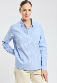 Chemise bleu clair à manches longues avec des rayures verticales blanches, col et poche poitrine. Tissu lisse avec une coupe classique.