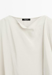 Blouse gris clair avec un design drapé, texture douce et encolure large. L'étiquette visible au niveau de l'encolure indique "Massimo Dutti."