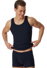Débardeur bleu marine et shorts en boxer ; design ajusté, texture lisse, tissu extensible, marquage minimal sur la ceinture.