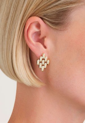 Boucles d'oreilles dorées avec des éléments ovales allongés de couleur crème disposés en motif de treillis, créant une apparence texturée.