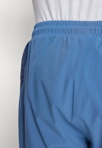 Lichtgewicht blauwe shorts met een elastische tailleband, een zachte textuur en subtiele plooien. Inclusief een marineblauw paneel aan de zijkant.