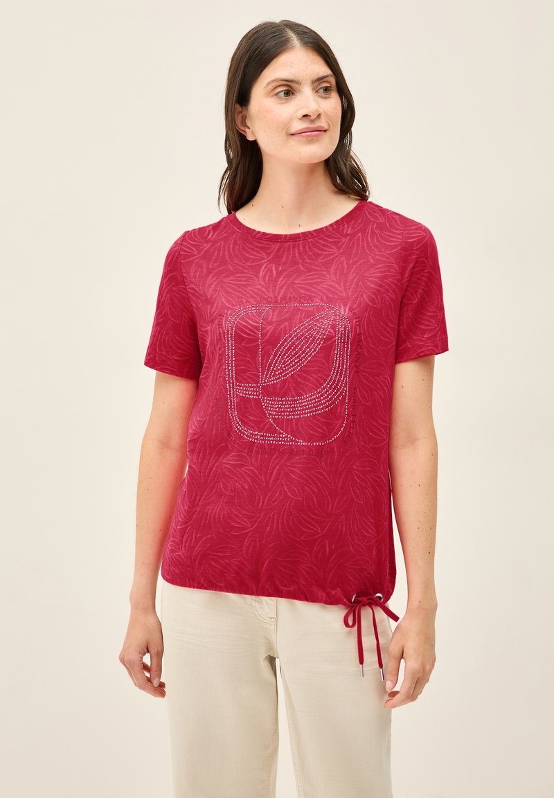 Rød kortærmet t-shirt med bladmønster og et dekorativt design i rhinsten foran. Inkluderer snøre i kanten.