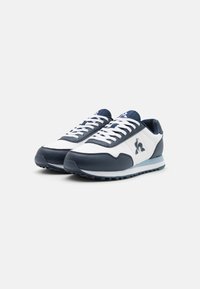 Sneaker blu navy e bianchi realizzati con materiali in pelle e tessuto. Design a contrasto con punta rotonda, chiusura con lacci e dettaglio logo.