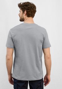 Šedé bavlněné tričko s krátkým rukávem, kulatým výstřihem a hladkou texturou. Žádné viditelné vzory nebo grafika. Pouze zadní pohled.