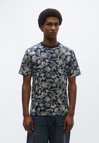 Μπλε ναυτικό κοντομάνικο μπλουζάκι με λουλουδάτο σχέδιο σε ανοιχτό εκρού, στρογγυλή λαιμόκοψη, μαλακή υφή, άνετη εφαρμογή και casual στυλ.