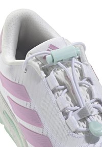 Zapatilla deportiva blanca con material de malla suave, acentos en rosa, un sistema de cordones único con un regulador azul claro y una suela texturizada.