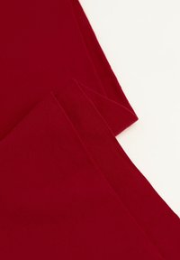 Tessuto elasticizzato borgogna, texture liscia, primo piano di un materiale piegato con bordi netti, design leggero e aderente.