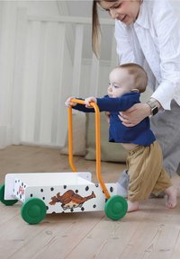Trækvogn i træ med et orange håndtag, grønne hjul og en hvid krop med sorte prikker samt et tegneseriefigursdesign.