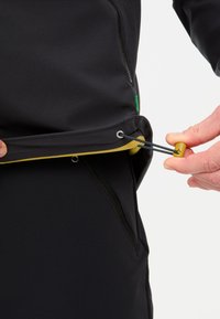 Zwarte jas met een gele voering, voorzien van een zijrits zak en een verstelbare koord onderaan. Glad textuur met reflecterende accenten.