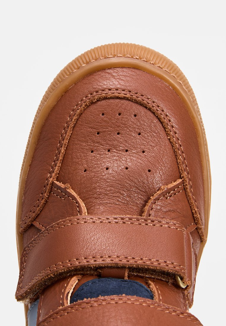 Baskets en cuir marron avec une sangle auto-agrippante, un bout perforé et une semelle en gomme texturée pour l'adhérence. Accentué par des panneaux en tissu bleu marine.