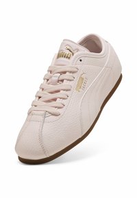 Różowy skórzany sneaker Puma z teksturowaną powierzchnią, klasycznym sznurowaniem, wyściełanym kołnierzem i złotymi akcentami z logo. Brązowa gumowa podeszwa.