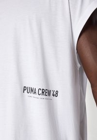 T-shirt en coton blanc à manches courtes et col rond. Le texte noir indique "PUMA CREW '48" et "PUMA TRAINING CREW SINCE 1948".