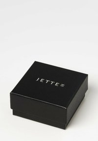 Schwarze rechteckige Schmuckbox mit strukturierten Oberflächen. Der Deckel verfügt über silberne prägierte Schrift "JETTE". Kompaktes Design, minimalistische Stil.