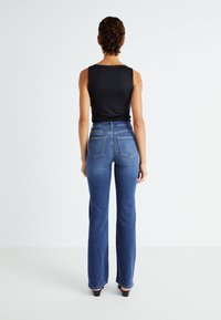 Jeans taille haute de couleur bleu foncé avec une coupe droite, fabriqués en denim. Présentent deux poches arrière et un design classique à cinq poches.