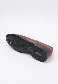 Zapato de cuero marrón con una suela de goma negra. La suela presenta un patrón texturizado y un acento azul con la palabra "Impermeable" grabada.