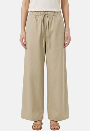 Pantaloni beige a gamba larga con vita elastica e coulisse, indossati con sandali color cammello e una maglia bianca, mostrati dalla vita in giù.