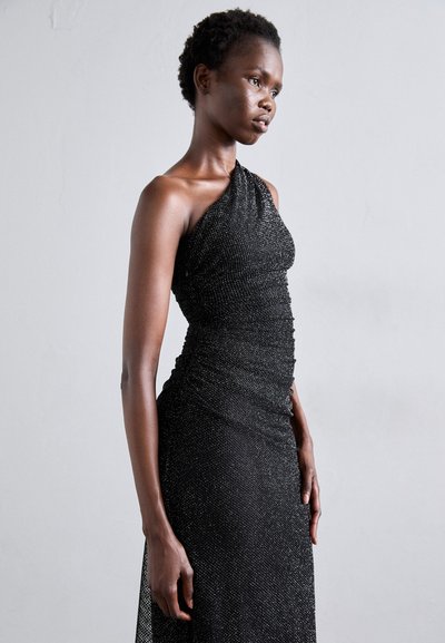 Svart, axelbandslös kvällsklänning med en ruchad design och metalltrådar för textur. Slät siluett med en figursydd bodice.