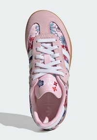 Sneaker in suede rosa con strisce bianche, stampa floreale in rosa, blu e rosso, con lacci bianchi e suola in gomma color caramello.