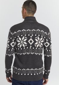 Grauer Strickpullover mit hohem Kragen, der ein weißes Schneeflockenmuster auf dem Rücken sowie gerippte Bündchen und Saum aufweist.